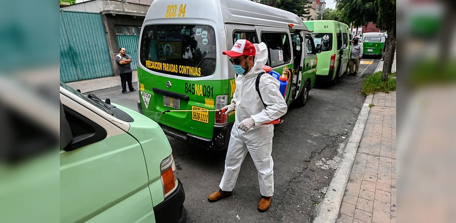 A cleaning worker wearing personal protective equipment (PPE) disinfects a public tranport vans in Mexico City. Credit: AFP