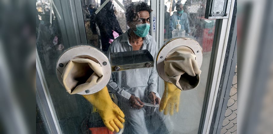 A man waits for a health worker to take a swab sample to test for the COVID-19 coronavirus at a testing point in Karachi. Credit: AFP