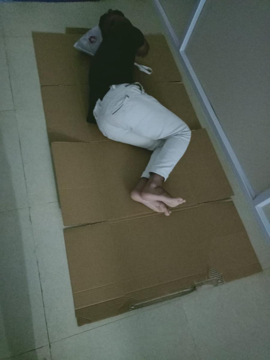 A covid patient, employee of Himat Singh Ka Linens, sleeps on the floor in Hassan.