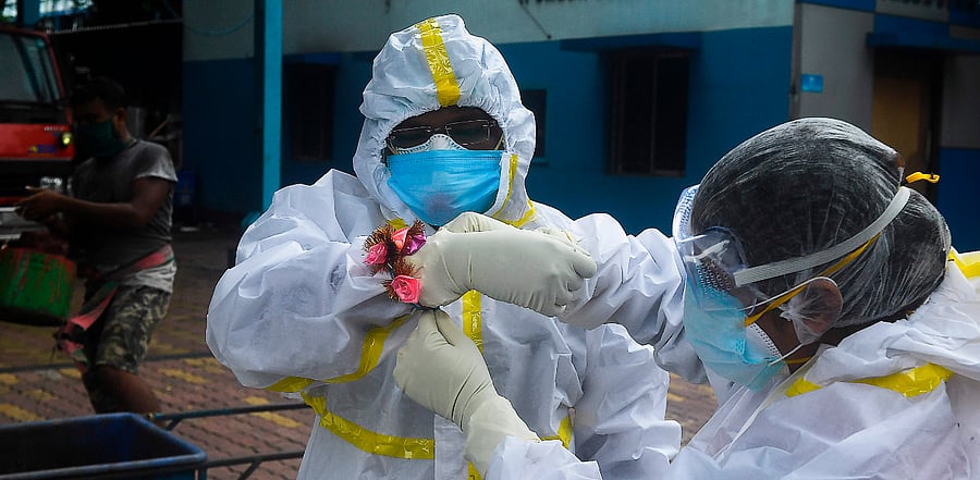 A health worker (R) ties a 'rakhi' (sacred thread) on the wrist of her coworker before collecting swab samples for Covid-19. Credit: AFP Photo