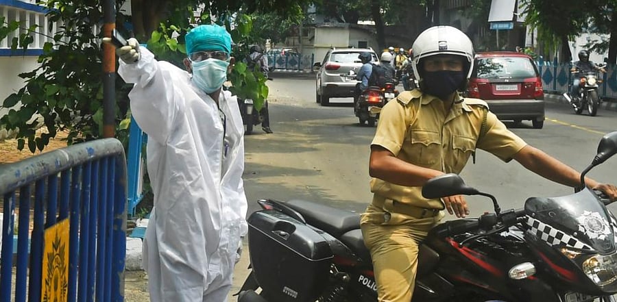 A health worker wearing a protective suit gives road directions to a policeman before the start of testing for the COVID-19. Credit: AFP