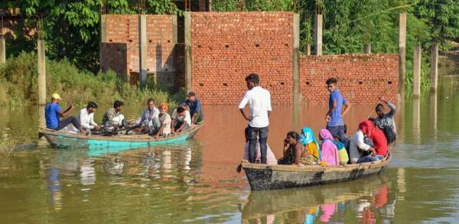 Flood-affected people ride on a boat on the banks of Rapti river to move to a safer place, in Gorakhpur. Credit: PTI Photo