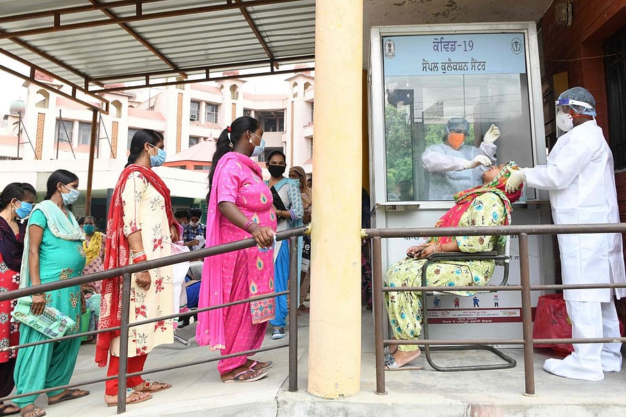 Health officials (R) collect a nasal swab sample from a woman to test for the coronavirus, at a civil hospital in Amritsar on July 31, 2020. Credit: AFP Photo