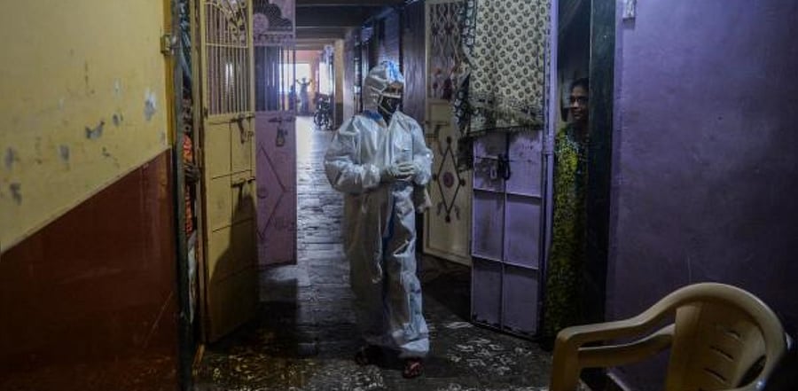 A health worker wearing a Personal Protective Equipments (PPE) suit interact with a resident during a door-to-door coronavirus screening in Dharavi slum area in Mumbai. Credit: AFP