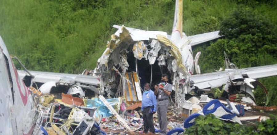 Officials stand on the debris of the Air India Express flight that skidded off a runway while landing at the airport in Kozhikode, Kerala. Credit: AP Photo