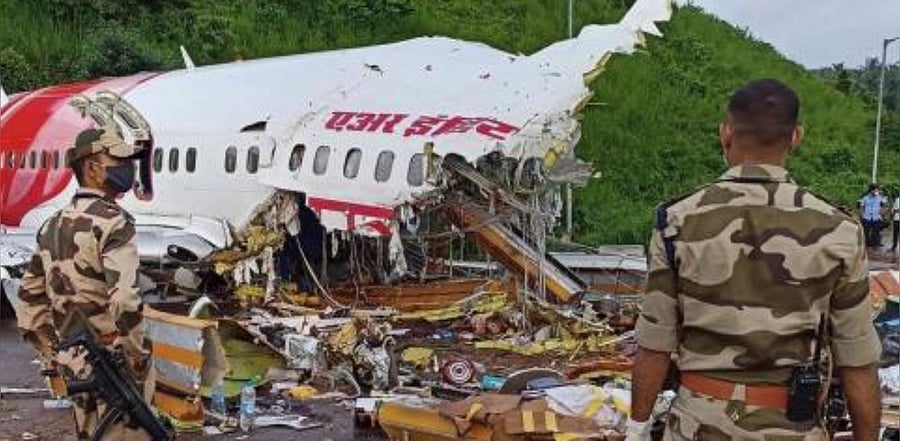 Security personnel stand guard near the mangled remains of an Air India Express flight, en route from Dubai. Credit: PTI Photo