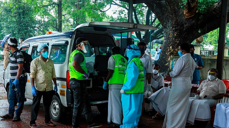 Medical staff wearing Personal Protective Equipment (PPE) equipment prepare to carry the body of a victim inside the medical college where victims of the Air India Express jet crash. Credits: AFP Photo