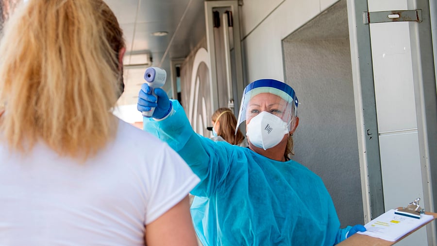 health worker takes a patient's temperature before sending them to a tent to be tested at a Covid-19 testing. Credits: Reuters Photo