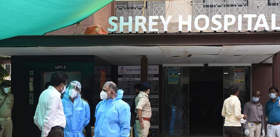 Forensic Science Laboratory PPE suits talk with a police official after a fire broke early in the morning in the intensive care unit of the Shrey Hospital. Credit: AFP