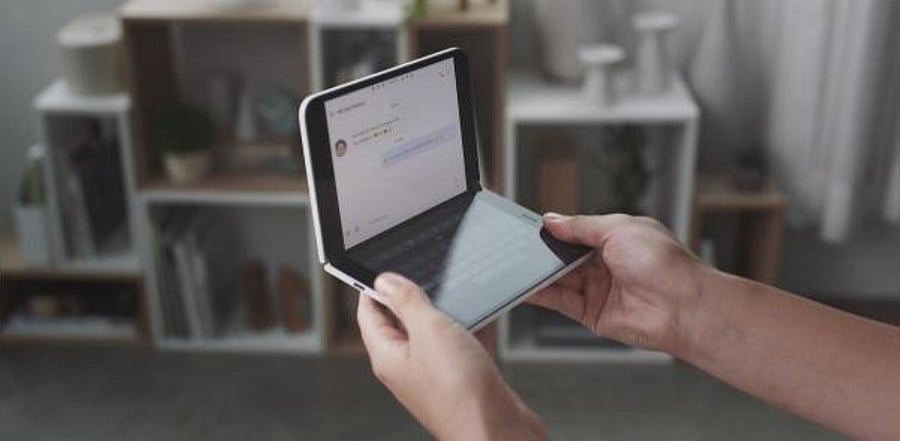Microsoft shows a woman looking at a new dual-screen device Surface Duo. Credit: AFP