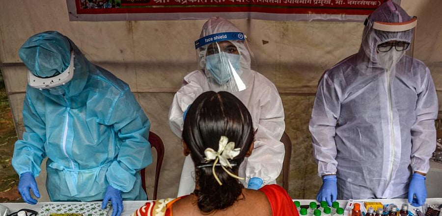 Health workers wearing Personal Protective Equipment (PPE) suits write down the details of a resident during a  coronavirus screening in Mumbai on August 12, 2020. Credit: AFP Photo