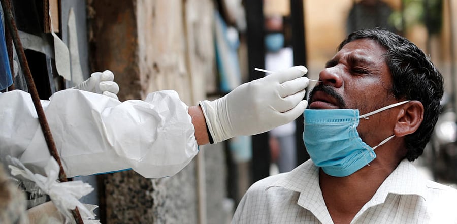 A health worker in personal protective equipment (PPE) collects a sample using a swab from a person at a local health centre to conduct tests for the coronavirus disease, amid the spread of the disease, in the old quarters of Delhi, India, August 14, 2020. Credit: Reuters File Photo