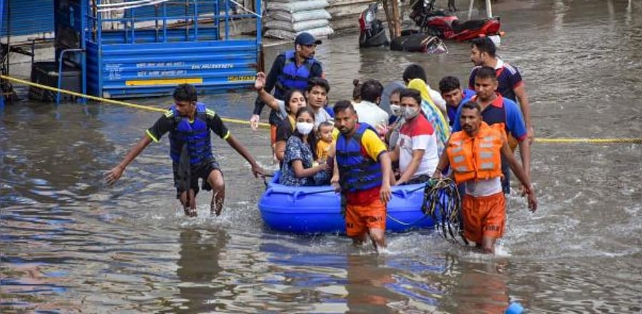Firefighters rescue people from flood-affected Parvat area following heavy rains, in Surat. Credit: PTI Photo