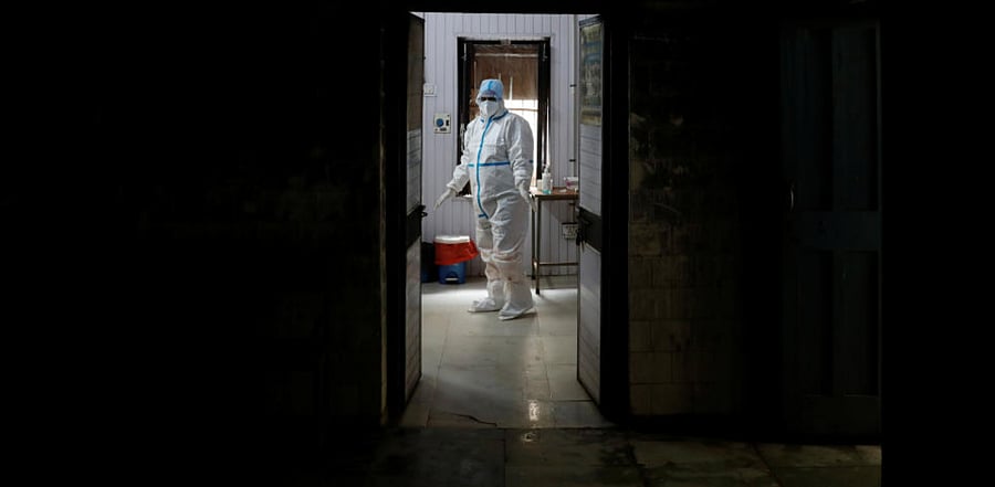 A health worker in personal protective equipment (PPE) waits at a local health centre for the next person to be tested for the coronavirus disease amid the spread of the disease, in the old quarters of Delhi. Credit: Reuters Photo