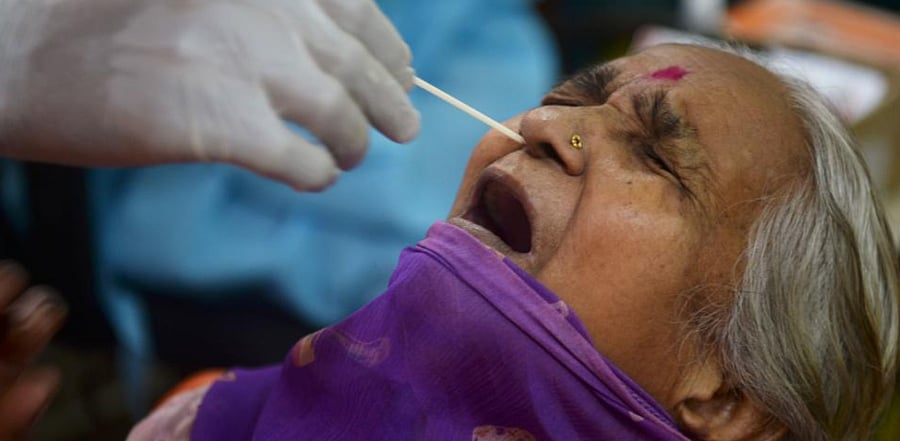 A health worker collects a swab sample of a resident to test for COVID-19 coronavirus, at a screening camp in Mumbai on August 17, 2020. Credit: AFP Photo