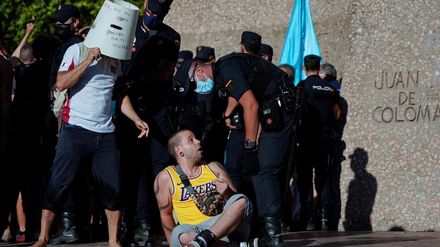 A police officer speaks with a demonstrator at a protest against the use of protective masks during the Covid-19 pandemic, in Madrid. Credit: Reuters