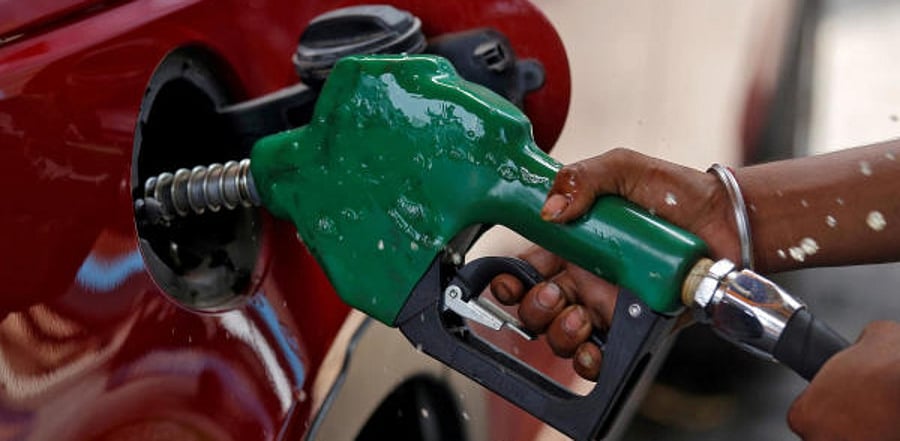 A worker holds a nozzle to pump petrol into a vehicle at a fuel station in Mumbai. Credit: Reuters