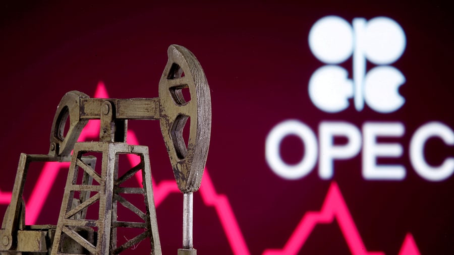 A 3D printed oil pump jack is seen in front of displayed stock graph and Opec logo. Credits: Reuters Photo