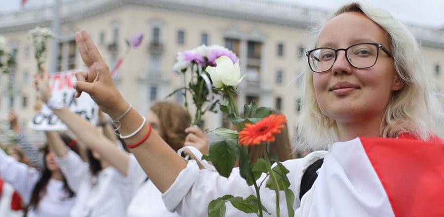  Belarusian opposition supporters hold flowers and flash victory signs during a protest in Victory Square in Minsk, Belarus. Credit: AP
