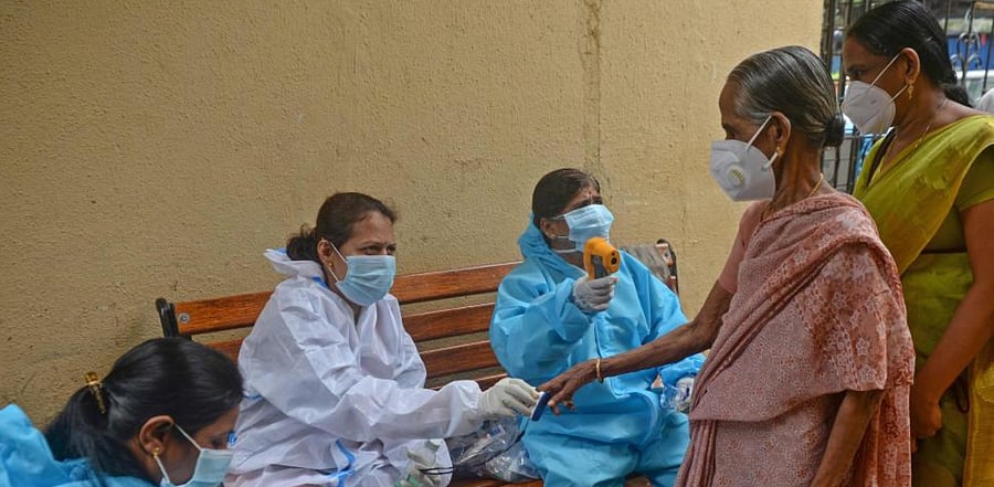 Health workers wearing protective gear use fingertip pulse oximeter and check the body temperature of residents during a coronavirus screening at Dharavi slums in Mumbai on August 18, 2020. Credit: AFP Photo