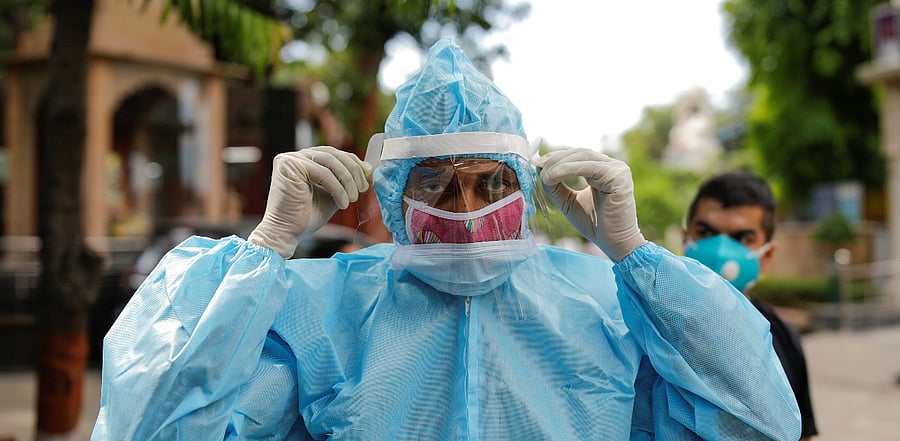 A relative wearing personal protective equipment (PPE) adjusts his protective face shield before the cremation of a man who died due to coronavirus disease in New Delhi. Credit: Reuters