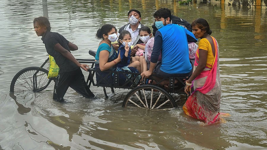 A rickshaw puller wades through a waterlogged street after heavy rainfall. Credits: PTI Photo