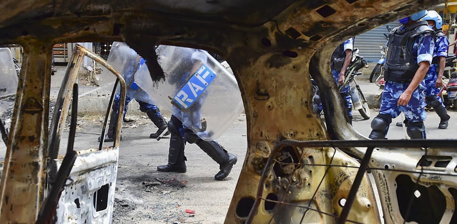  Rapid Action Force (RAF) personnel carry out a flag march in the riot-hit area after a mob went on a rampage on Tuesday over a social media post, allegedly posted by a Congress MLA's relative, in Bengaluru, Thursday, Aug. 13, 2020. Credit: PTI Photo