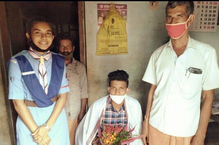 Scouts and Guides Ranger Shahana Mumthas felicitates SSLC topper Rakshith B R and presents her scholarship amount at the latter's house in Ajjavar near Sullia. Rakshith's father Ramesh is also seen.