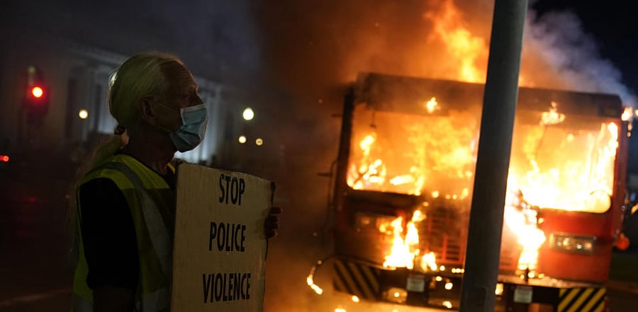 A protester stands near a burning garbage truck outside the Kenosha County Courthouse, late Monday, Aug. 24, 2020, in Kenosha, Wis. Credit: AP Photo
