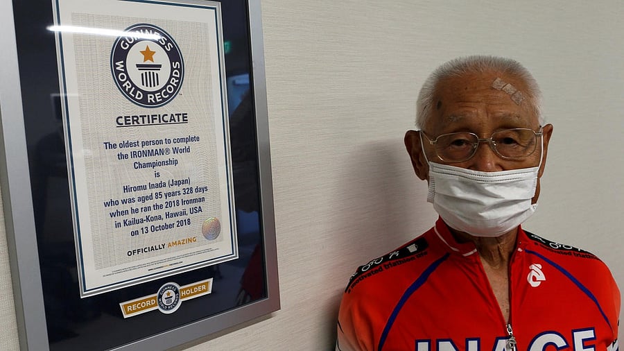 Hiromu Inada, redord holder of the oldest person to complete an Ironman World Championship, poses for a photograph next to his certificate from Guinness World Record in Chiba, Japan. Credit: Reuters