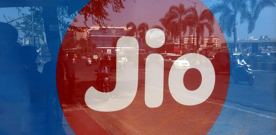 Commuters are reflected on an advertisement of Reliance Industries' Jio telecoms unit. Credits: Reuters