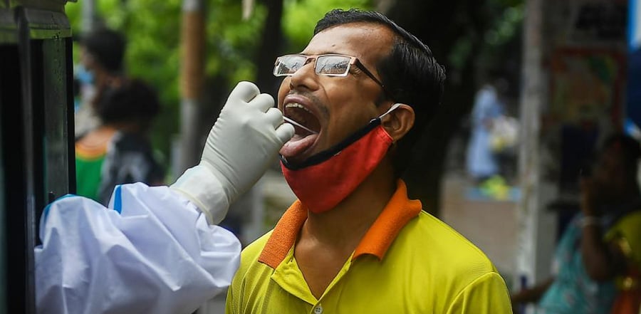 A health worker wearing a personal protective equipment (PPE) collects a swab sample of a man to test for the Covid-19. Credit: AFP