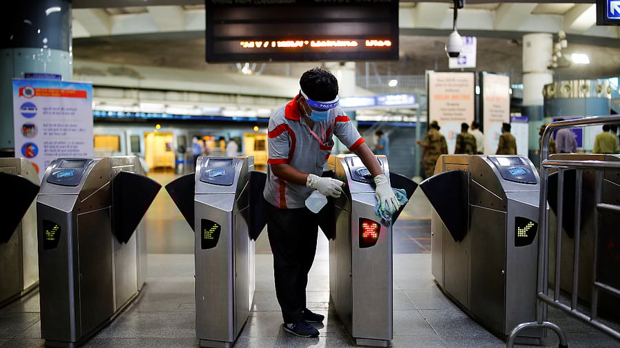 A worker cleans the entry gates at a Delhi Metro station ahead of the restart of its operations, amidst the spread of coronavirus disease. Credits: Reuters Photo
