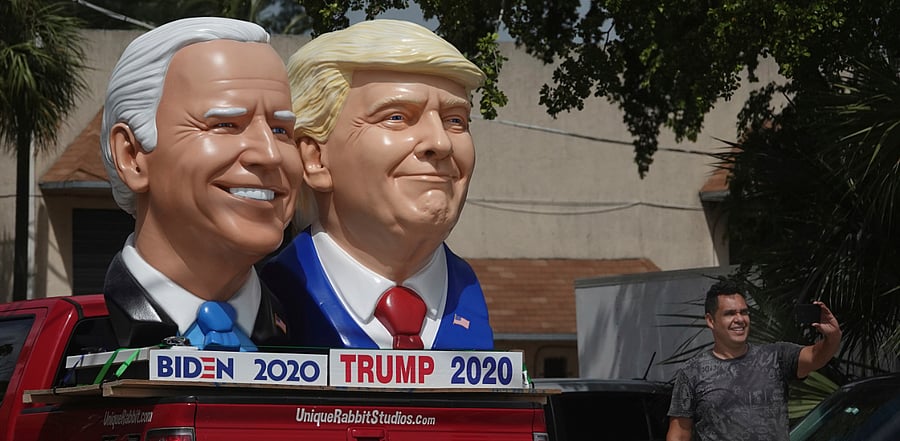 A passerby stops to take a selfie with foam sculpture depictions of President Donald Trump and Democratic presidential candidate former Vice President Joe Biden. Credit: AP Photo