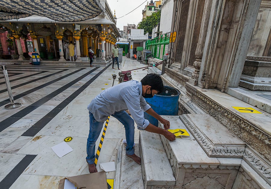 A worker pastes stickers on the floor of Hazrat Nizamuddin shrine to ensure social distancing ahead of its reopening, during unlock 4.0, in New Delhi, Saturday, Sept. 5, 2020. Credit: PTI Photo