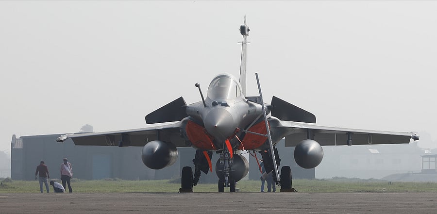 An Indian Air Force officer wearing a protective face mask walks in front of a Rafale fighter jet during its induction ceremony at an air force station in Ambala. Credit: Reuters Photo