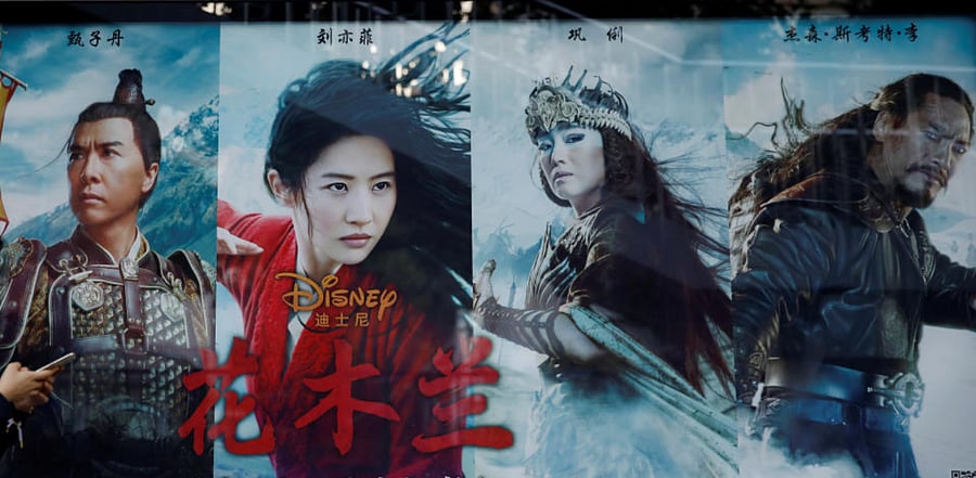 A woman walks past an advertisement promoting Disney's movie "Mulan" at a bus stop in Beijing, China. Credit: Reuters