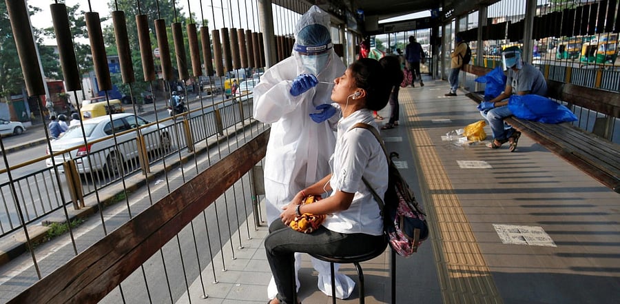 A healthcare worker wearing personal protective equipment (PPE) takes swab from a woman for a rapid antigen test. Credit: Reuters