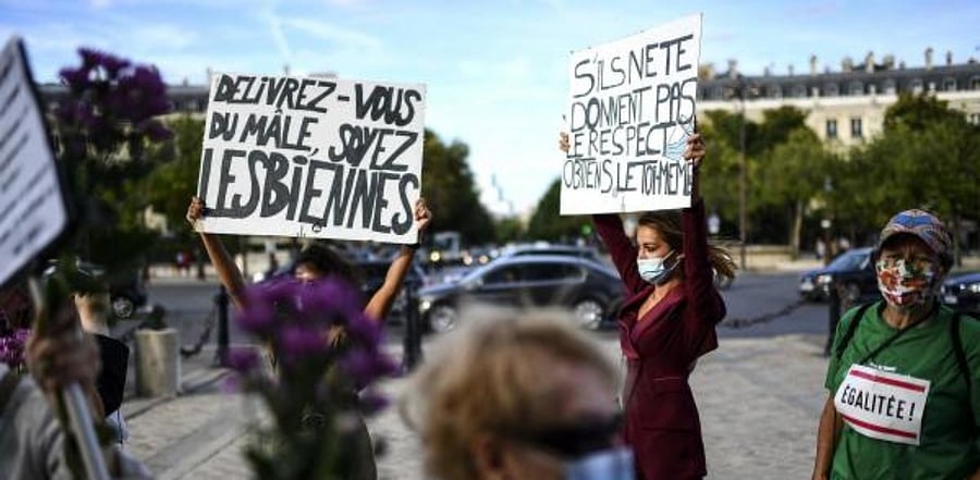 Activists hold placards reading "Free yourselves from the male, be lesbian" (L) and "If they don't give you respect, obtain it yourself" (R) during a gathering to mark the 50th anniversary of the first demonstration of French feminist movement Mouvement de Liberation des Femmes (MLF - Women's Liberation Movement) on the Place de l'Etoile, near the Arc de Triomphe, in Paris. Credit: AFP
