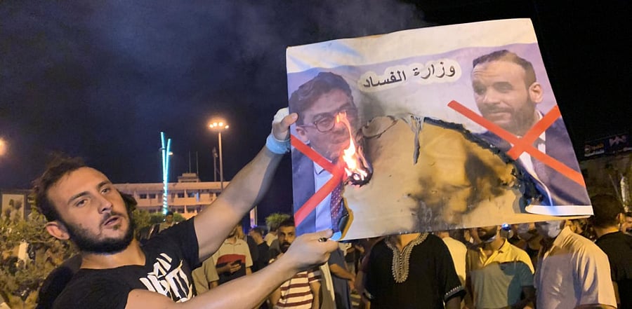 A Libyan protester burns an image of Libyan officials as he protests. Credit: Reuters