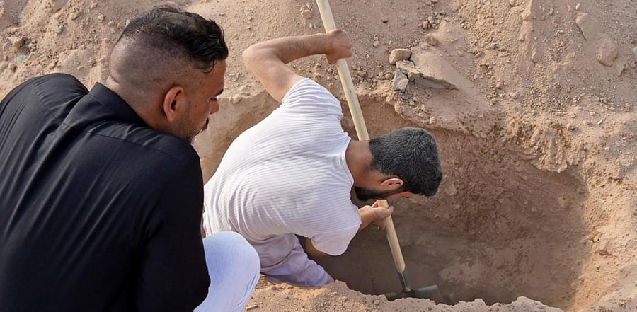 An Iraqi family digs up the corpse of a relative, who died of the novel coronavirus, at a coronavirus cemetery in a plot of desert outside the Shiite holy city of Najaf to be transferred to a family cemetery for reburial. Credit: AFP Photo