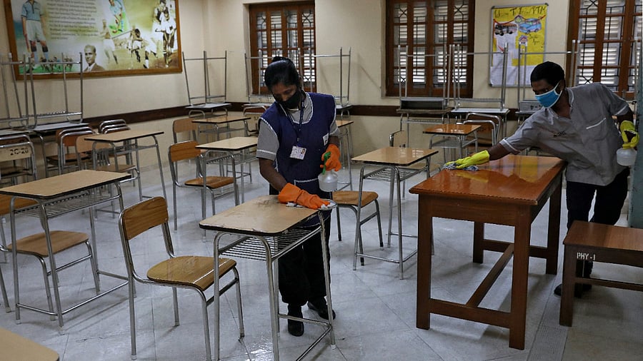 Workers wearing protective face masks disinfect chairs and tables inside an examination centre ahead of the National Eligibility cum Entrance Test (NEET), amidst the spread of the coronavirus disease. Credits: Reuters Photo