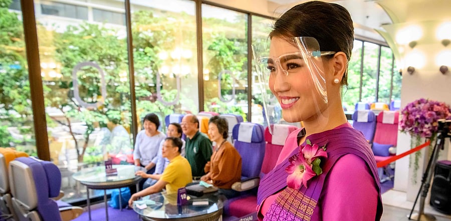 Thai Airways flight attendant wearing a face shield as she serves drinks at a pop-up air-plane-themed restaurant at the airline's headquarters in Bangkok. Credit: AFP Photo