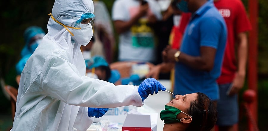 A medical staff wearing PPE takes a nasal swab sample from a resident for a Covid-19, in a residential area in Mumbai. Credit: PTI Photo