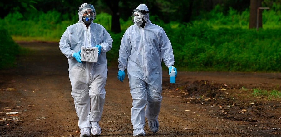 Medical staff wearing Personal Protective Equipment (PPE) carry nasal swab samples during a Covid-19 Coronavirus screening outside a quarantine centre, in Nashik. Credit: AFP Photo