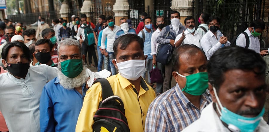 People wait in line to board a bus amidst Covid-19 in Mumbai. Credit: Reuters