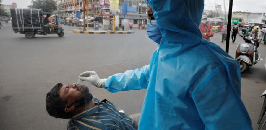 A healthcare worker wearing personal protective equipment (PPE) takes a swab from a man for a rapid antigen test alongside a road, amidst the coronavirus disease. Credit: Reuters Photo