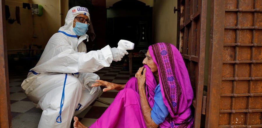 A healthcare worker wearing personal protective equipment (PPE) checks the temperature of a woman. Credit: Reuters
