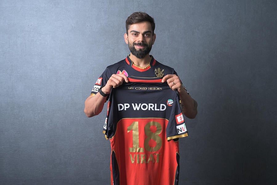 RCB skipper Virat Kohli shows the team's jersey with 'My Covid Heroes' emblazoned at the back during the launch on Thursday. RCB MEDIA