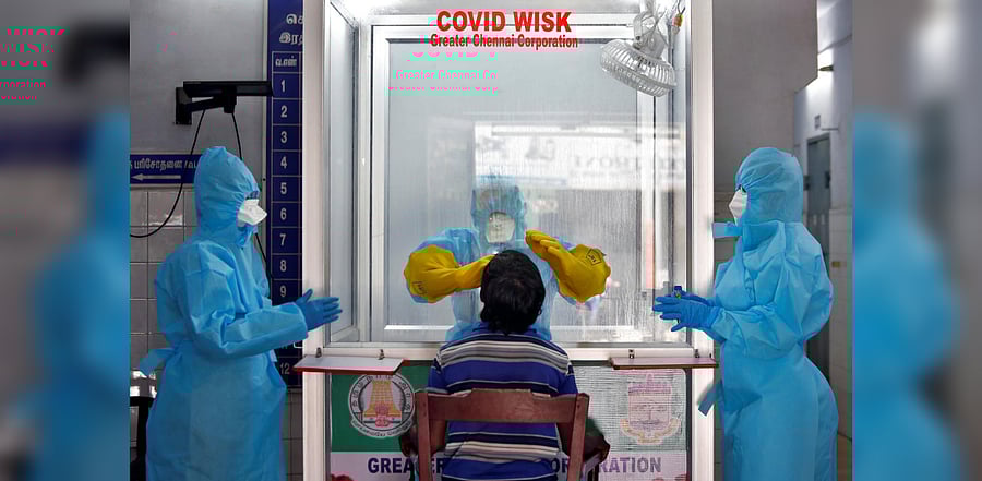 A doctor in a protective chamber takes a swab from a man to test for coronavirus disease. Credit: Reuters Photo